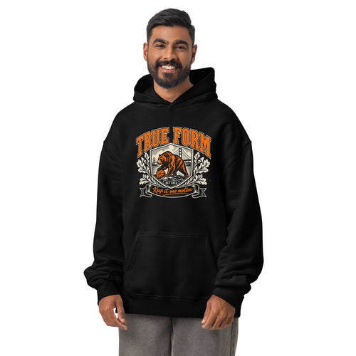 Model wearing the black True Form essential men's comfort hoodie with an orange True Form bear graphic and Keep it one motion lettering.