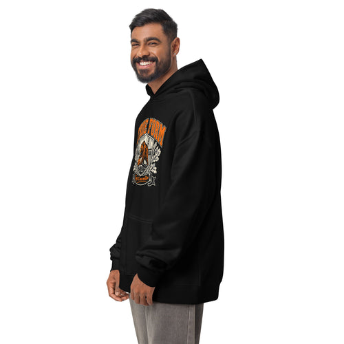 Model wearing the black True Form essential men's comfort hoodie with an orange True Form bear graphic and Keep it one motion lettering, shown from the left front.